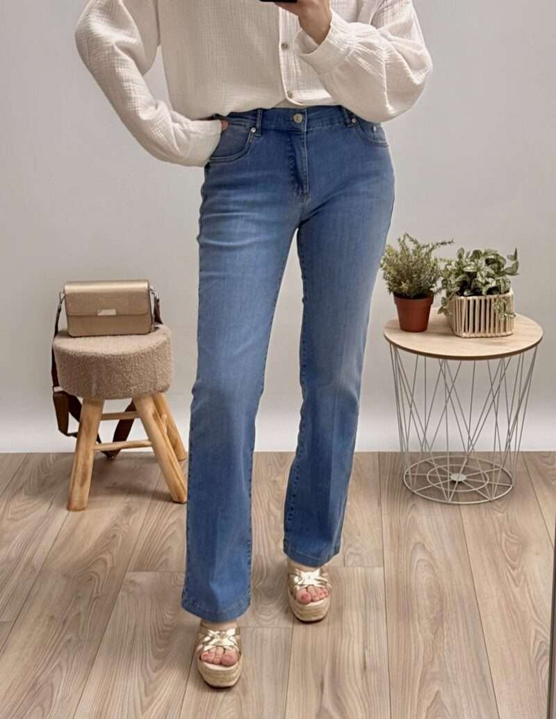 : jeans bleu coupe évasée anna montana, porté avec un pull blanc et des sandales compensées.
