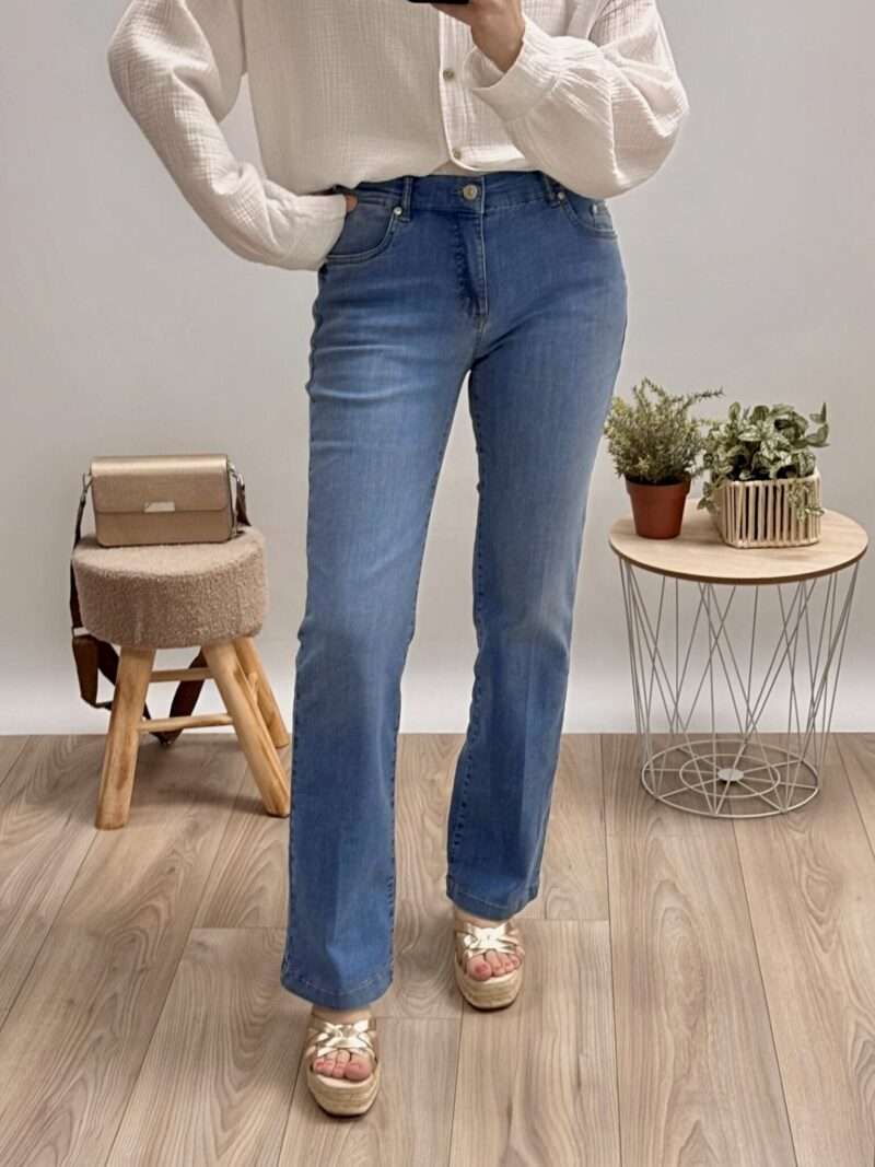 : jeans bleu coupe évasée anna montana, porté avec un pull blanc et des sandales compensées.