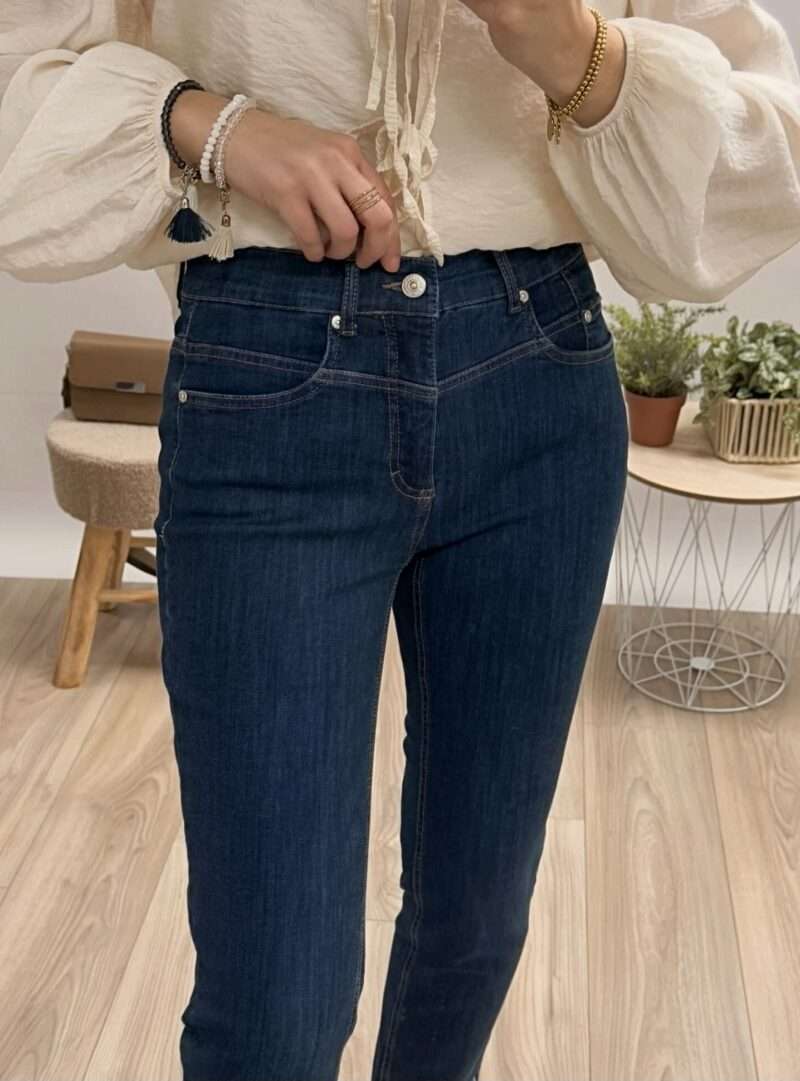 jeans bleu foncé coupe slim anna montana angelika, porté avec un chemisier beige à manches bouffantes et des sandales compensées.