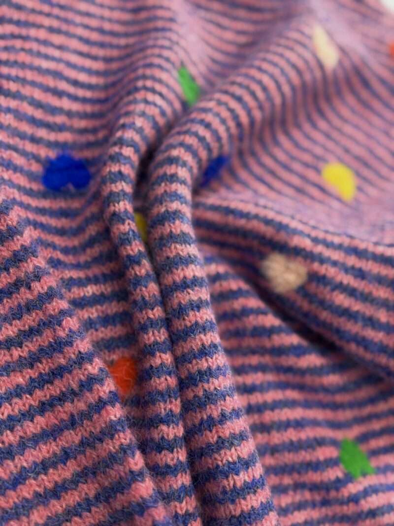 Détail de la maille pull tricot rose et bleu rayé avec motif cœurs et pois multicolores.