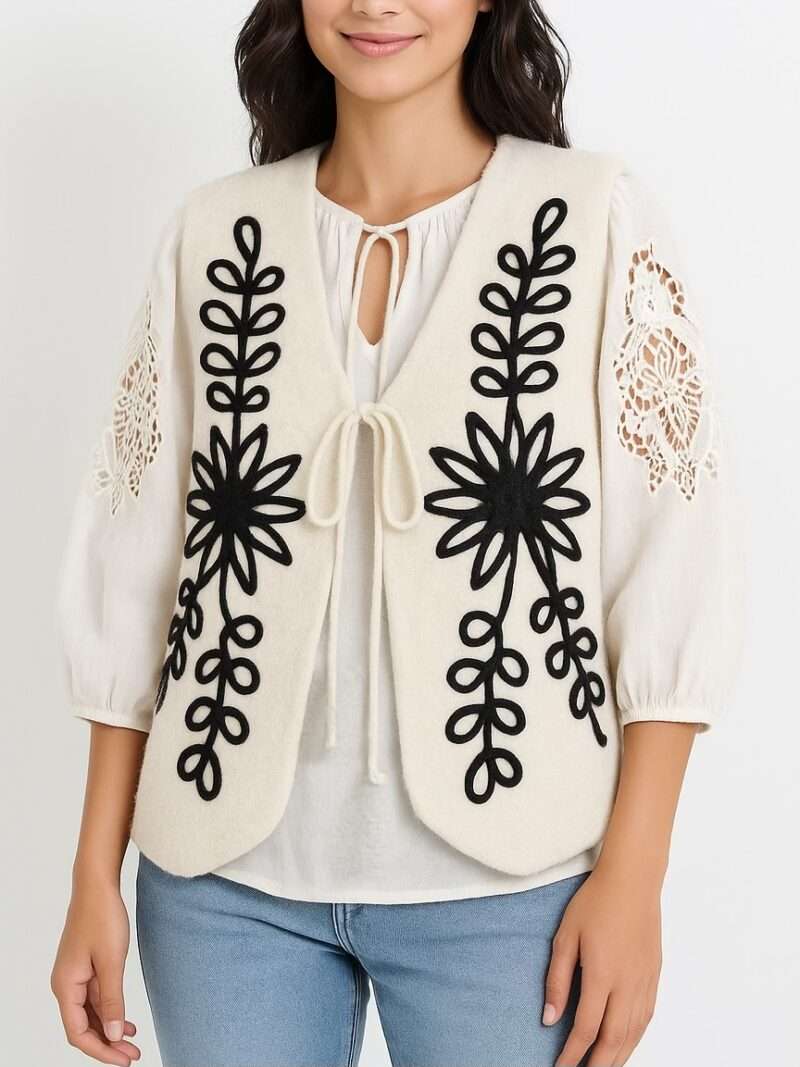Gilet sans manches feutre crème avec broderies noires florales/folkloriques, lacets devant, style bohème.