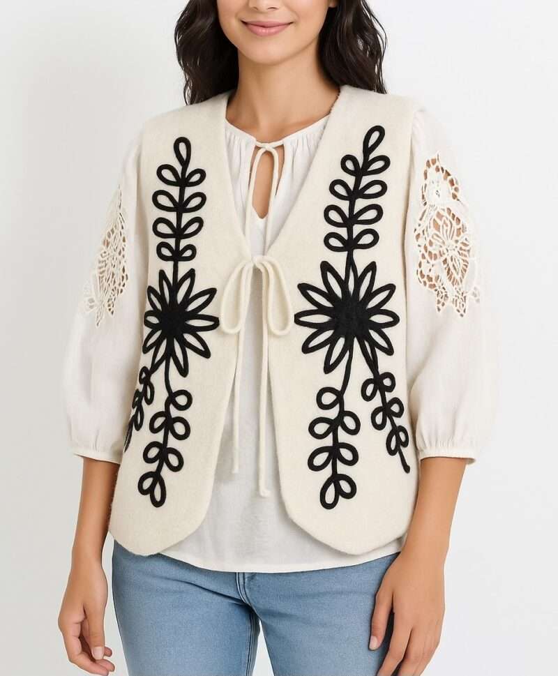 Gilet sans manches feutre crème avec broderies noires florales/folkloriques, lacets devant, style bohème.